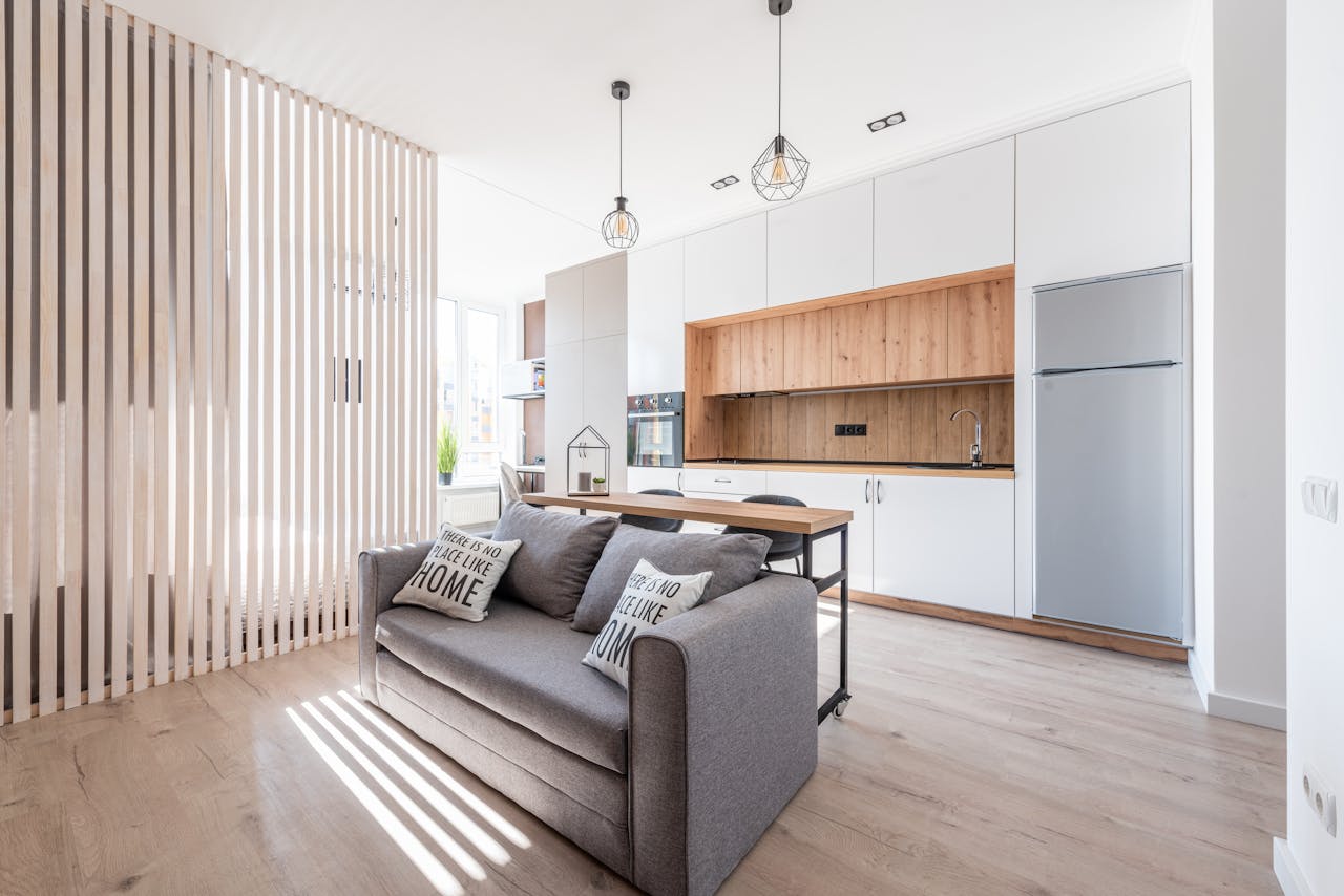 services-img Interior of contemporary open plan kitchen with white cabinets and cozy sofa with cushions in sunlight